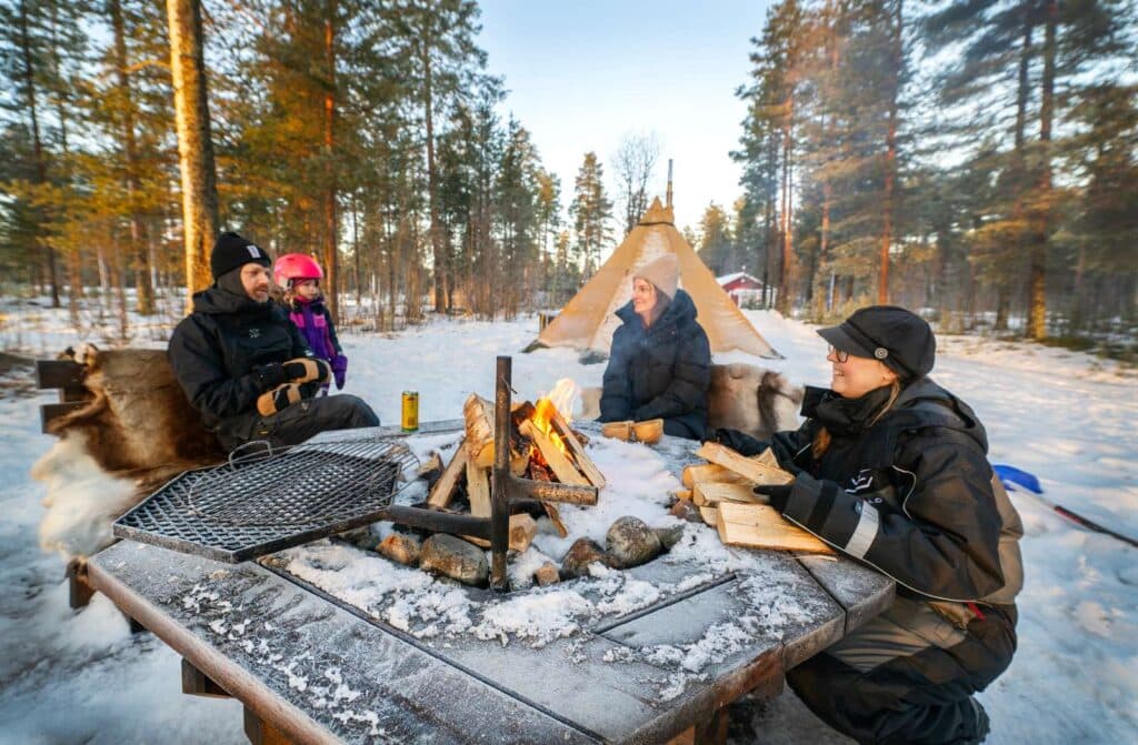 Familj som sitter och grillar i vinternaturen i luleå