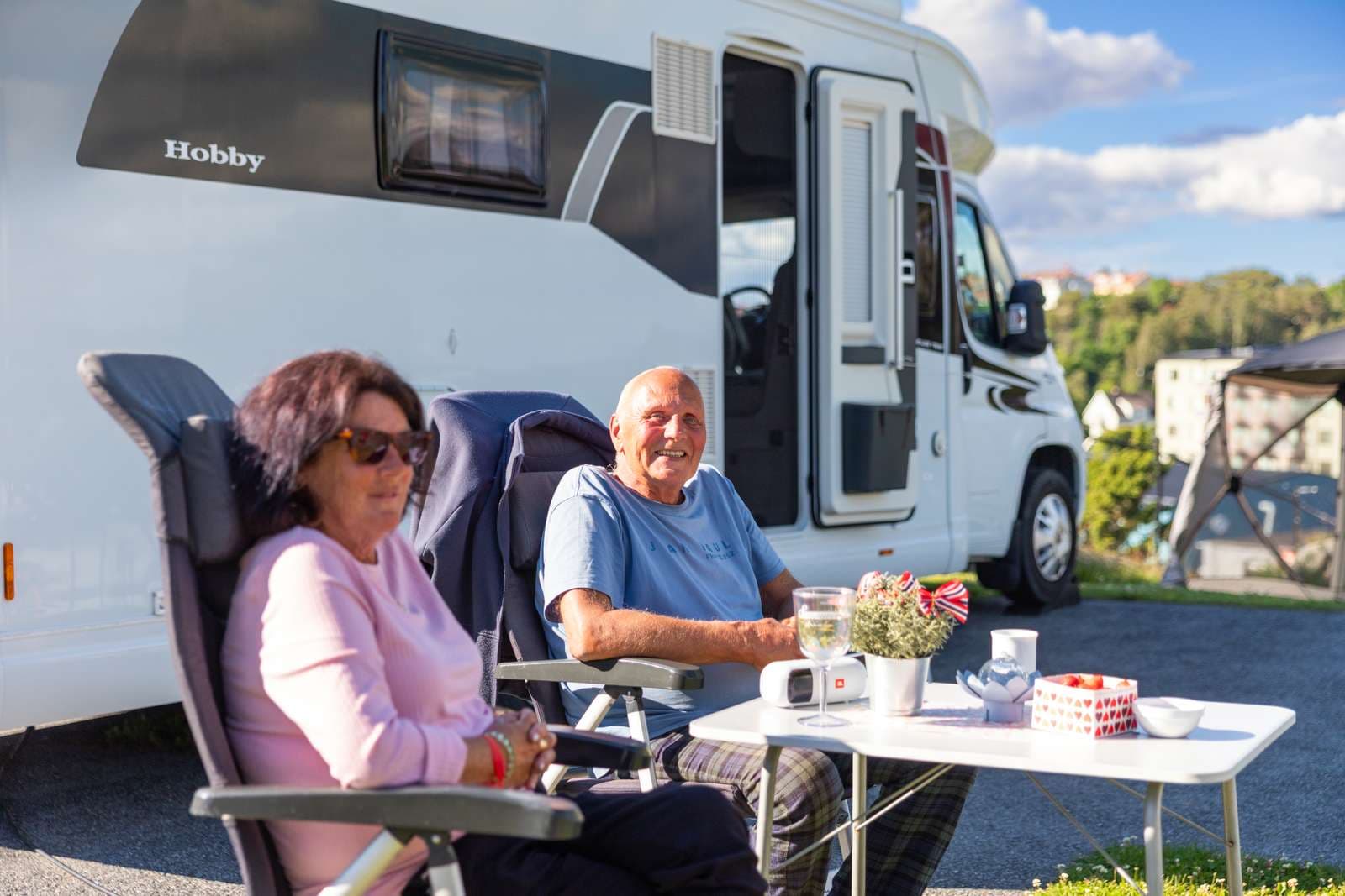 Två gäster som sitter utanför husbilen och njuter av campinglivet på City Strömstad