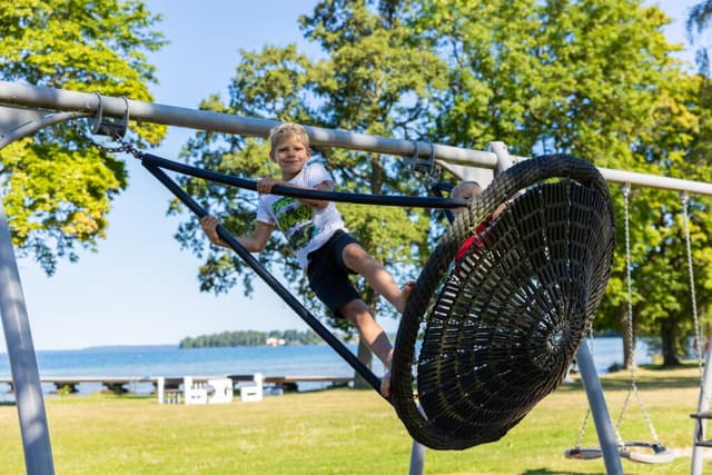 Barn i gunga på lekplats vid First Camp Vadstena - Vättern